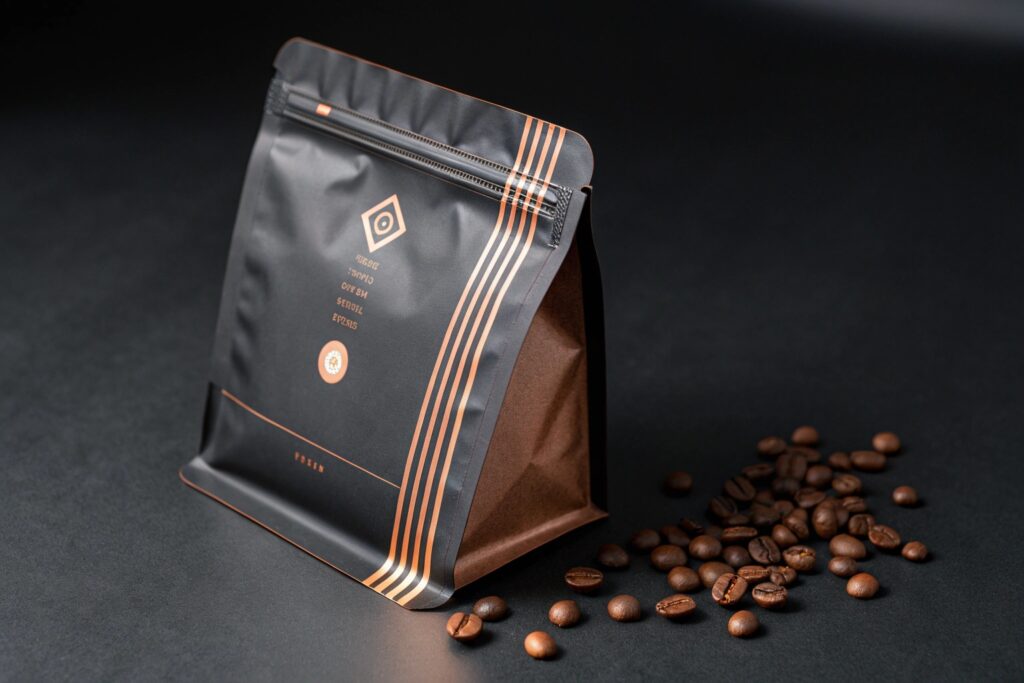 Matte black stand-up coffee pouch with copper accents and scattered roasted beans on dark background.