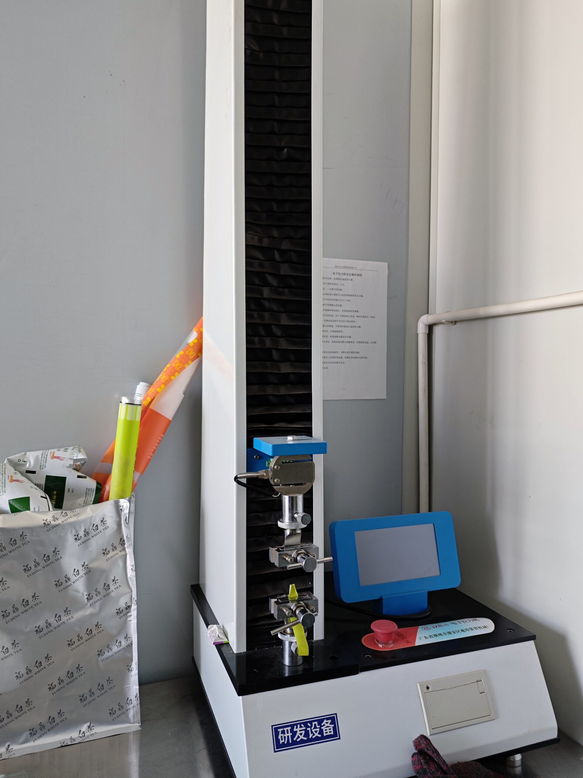 Tensile strength testing machine used for flexible packaging quality control in factory lab.