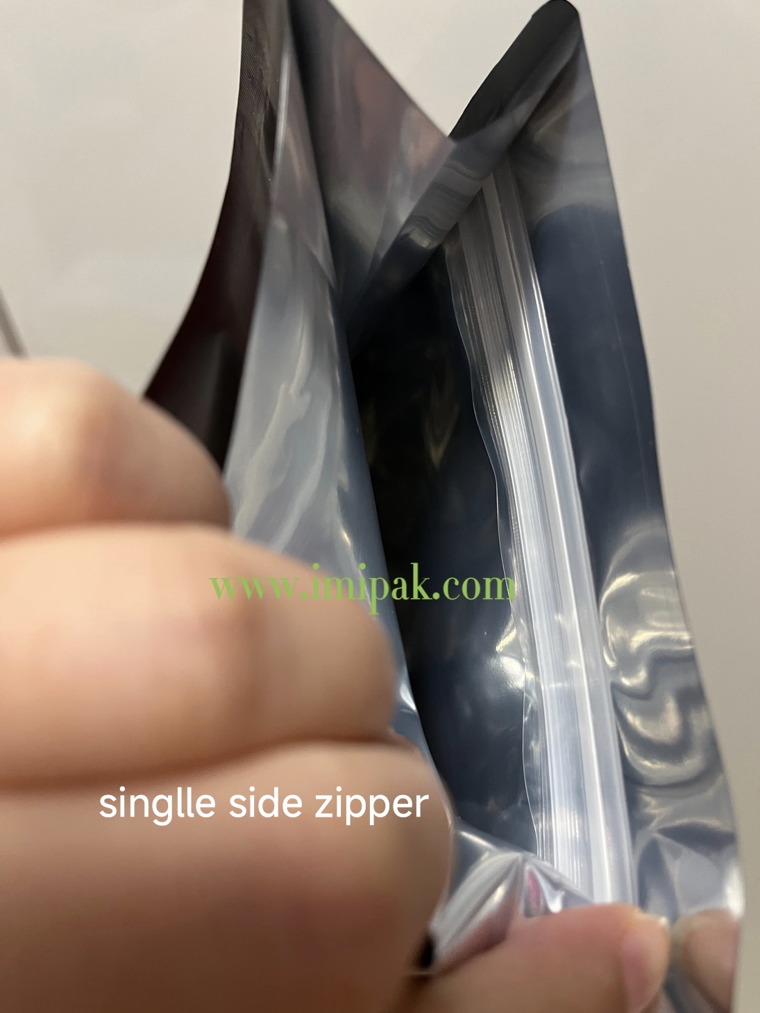 Close-up of flexible pouch with single side zipper seal, held open by hand for display.