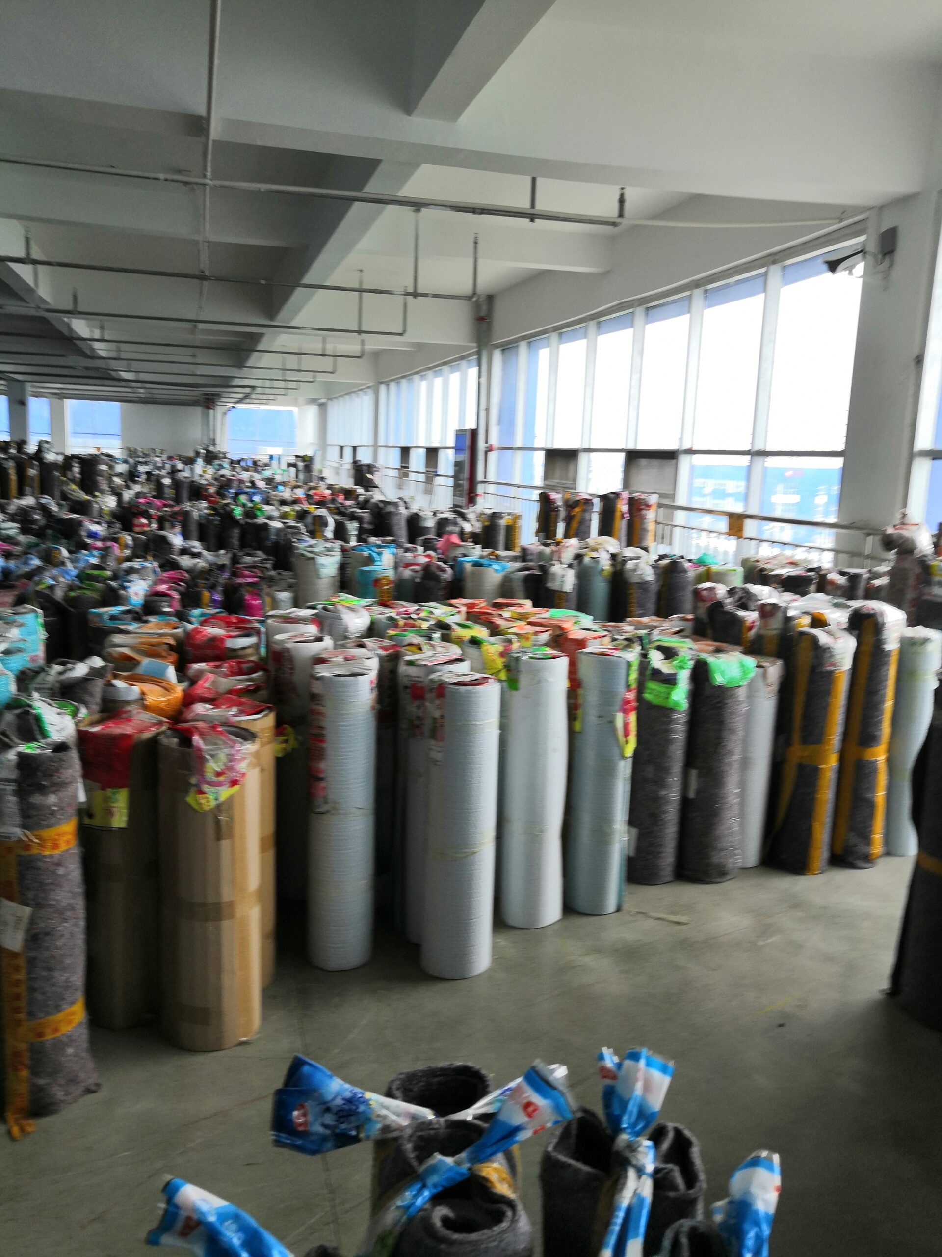 Large warehouse filled with rolls of printed laminated film for flexible packaging production.