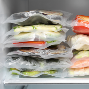 Vacuum sealed food bags with assorted vegetables neatly stacked in freezer storage.
