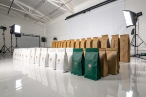Custom coffee packaging bags in kraft, white, and green materials arranged in a studio setting.