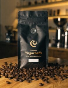 Black Ethiopian Yirgacheffe coffee pouch standing among roasted coffee beans